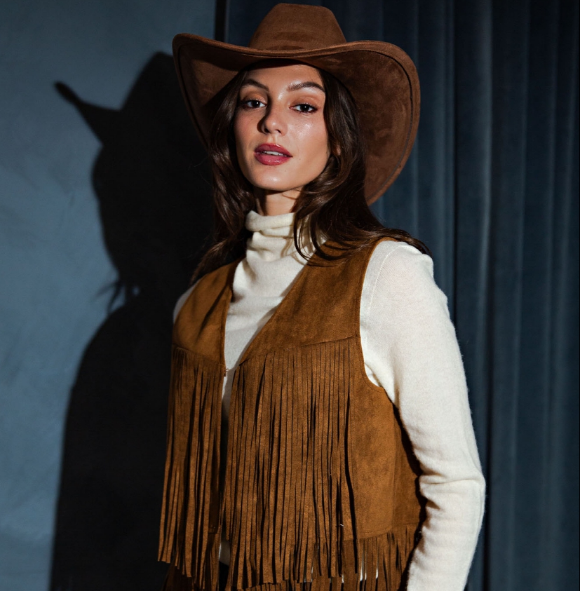 Brown suede vest featuring full-length fringe detailing and an open-front design, creating a western-inspired statement piece perfect for layering over tops or dresses.