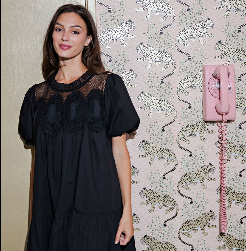 Black babydoll dress featuring delicate crochet lace yoke, sheer neckline detail, and soft bubble sleeves. Feminine, relaxed silhouette with a tiered skirt for an effortlessly chic boutique look.