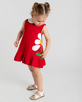 Young girl in a red dress with a white flower on a white background