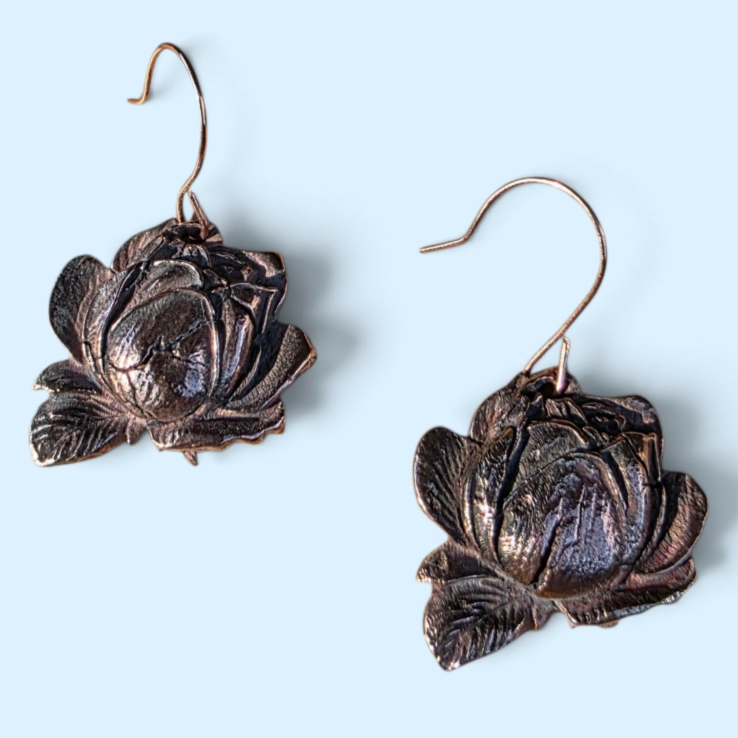Handcrafted bronze floral earrings featuring richly textured blooms, dimensional detail, and a darkened patina that highlights every petal. Lightweight statement pieces with a romantic, modern edge.